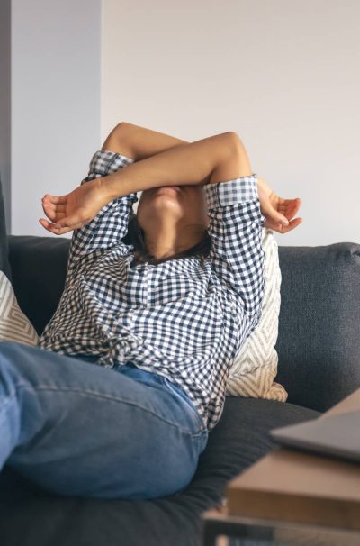 Tired from work, a young woman with a laptop lies on the couch.